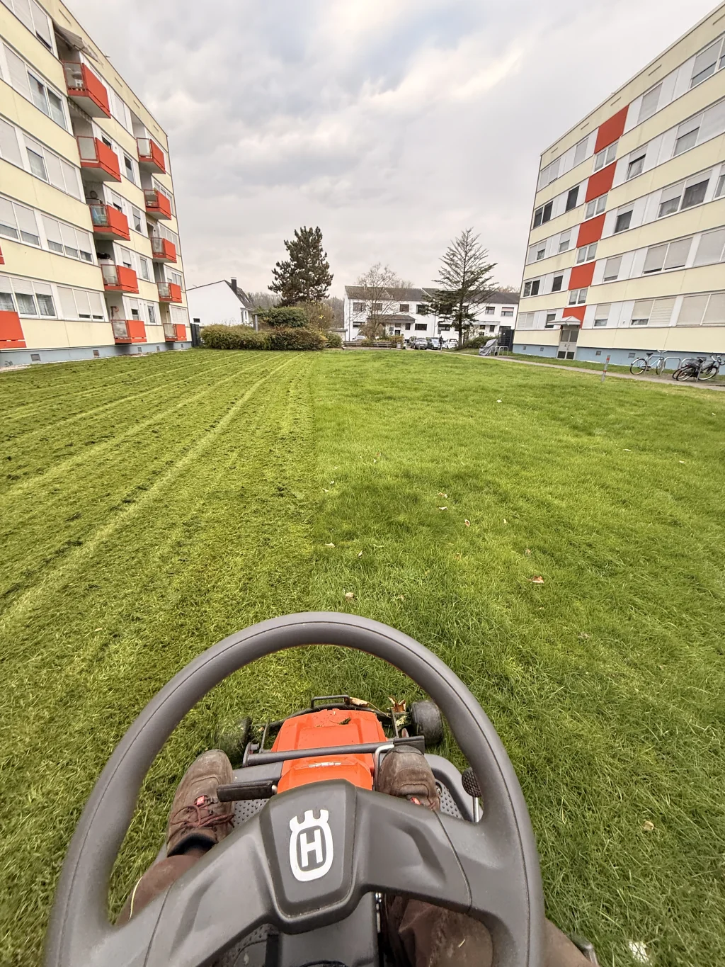 Rasenmähen mit Husqvarna-Aufsitzmäher bei einem Mehrfamilienhaus